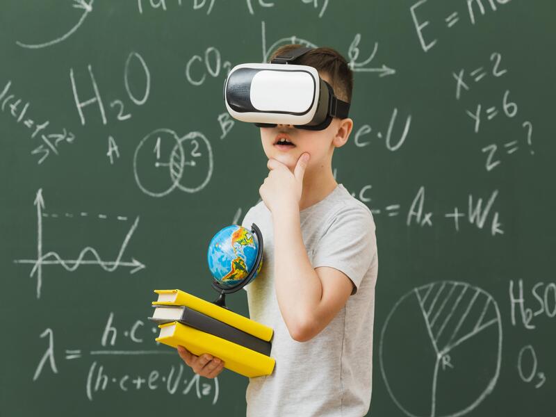 Junge mit VR-Brille auf und Büchern in der Hand